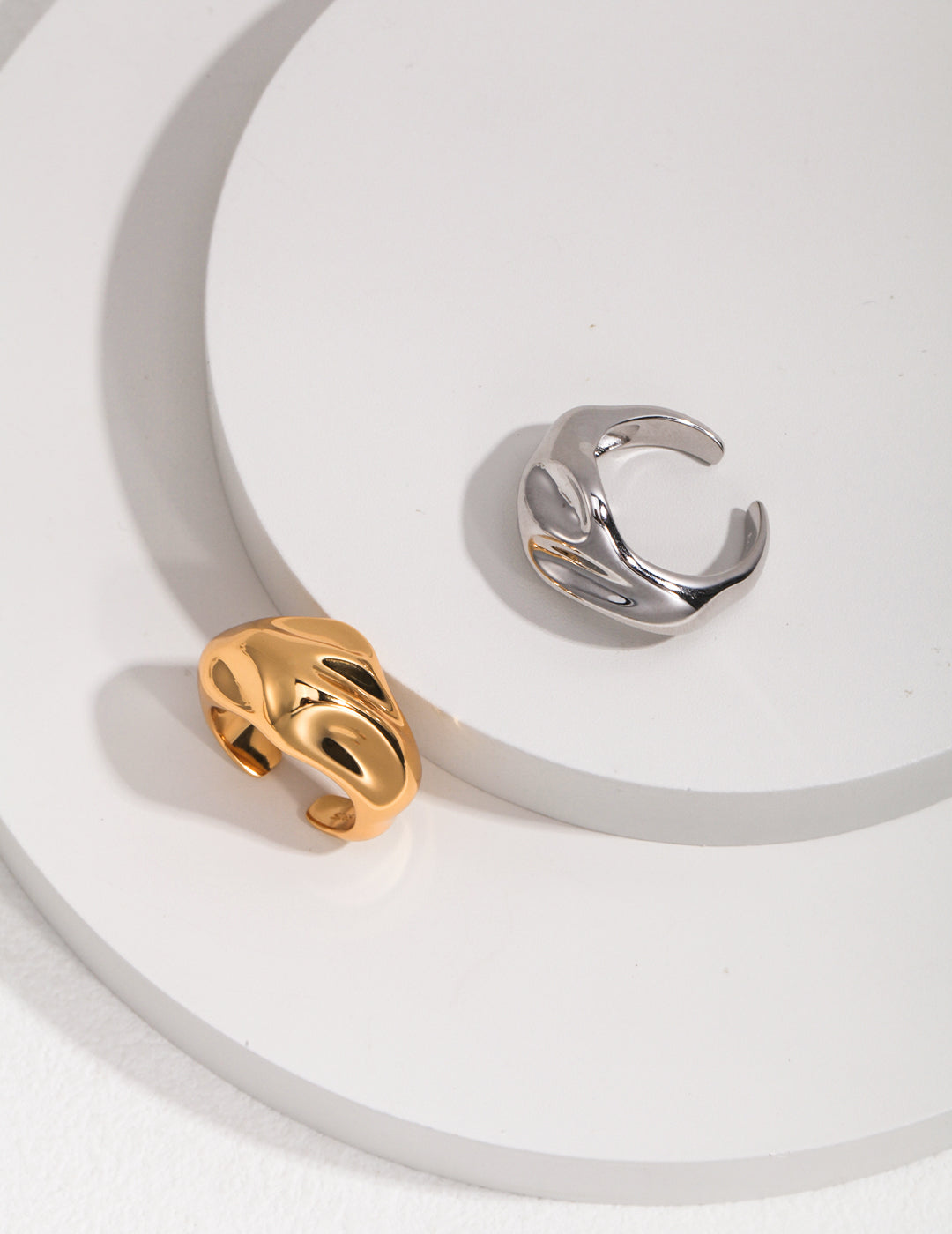 Two motion inspired rings with gold and silver designs on a white plate.