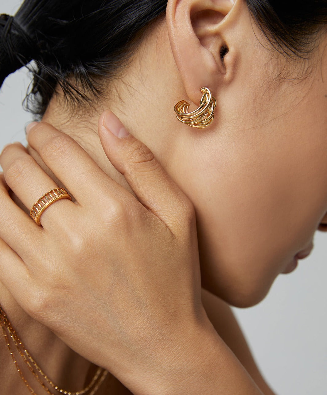 Woman adorned in gold jewelry set, featuring a gold earring.