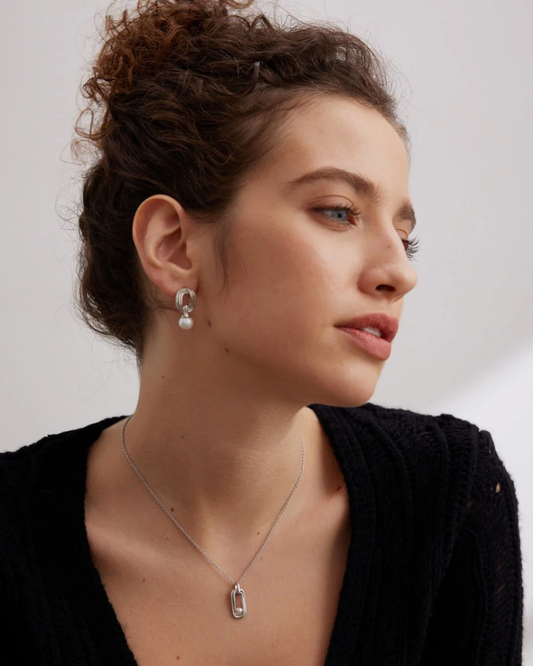 A woman adorned with an infinity sign necklace and earrings, highlighting her stylish accessories.