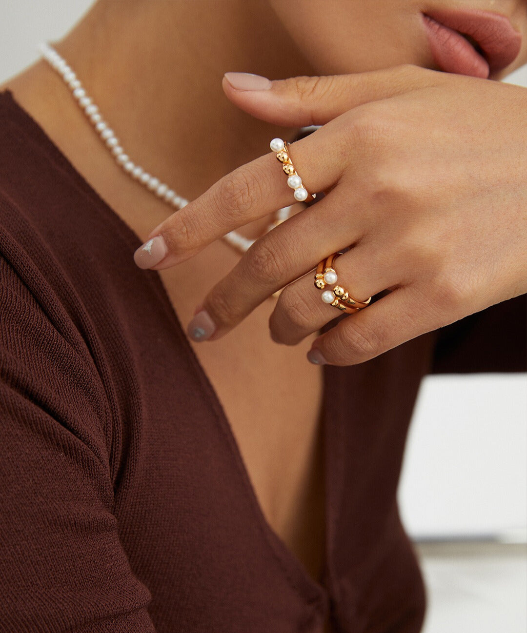 A model showcasing a gold ring adorned with dainty beads and freshwater pearls, complemented by a pearl necklace.