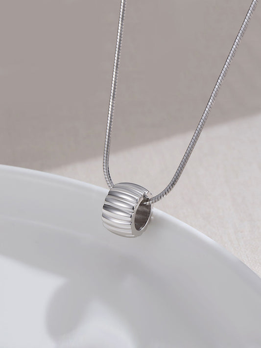 Shiny circular pendant on silver necklace, displayed on a plate.