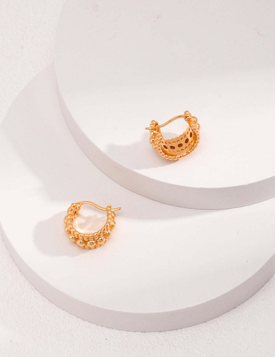 Gold plated hoop earrings with stacked bead layers on a white background.