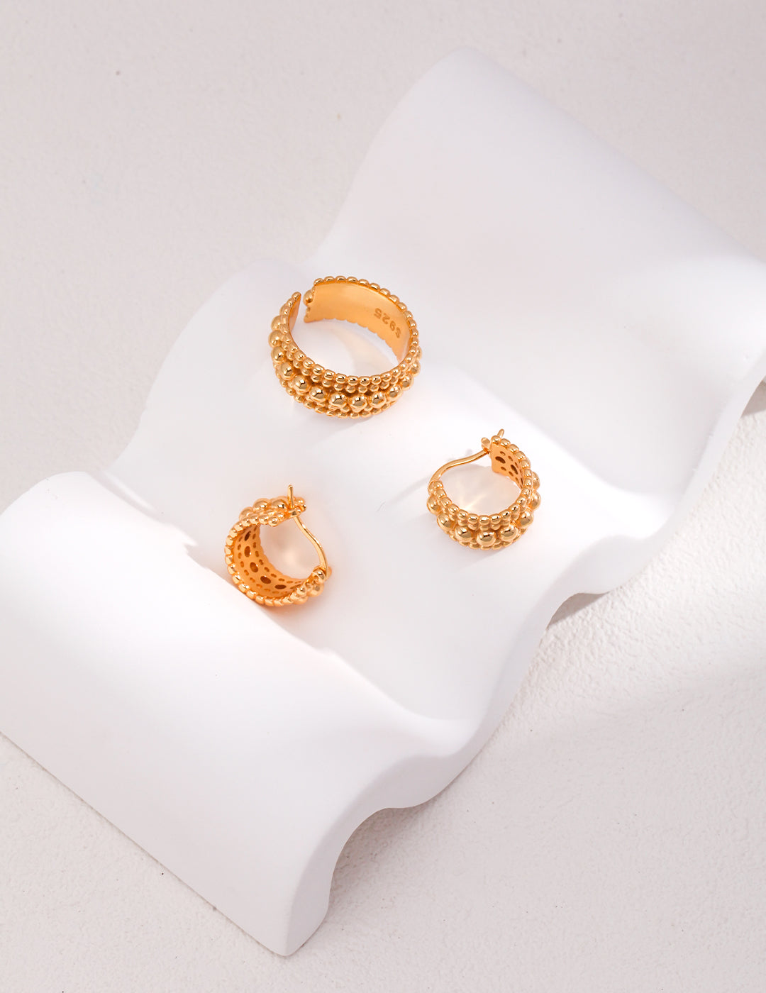 Stylish gold hoop earrings with bead layers and a coordinating ring on a clean white background.