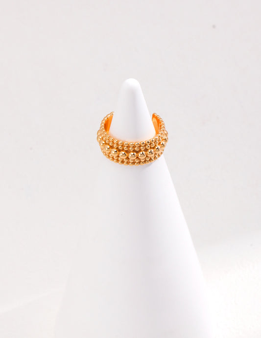 A gold-plated bead ring resting on a white cone, showcasing elegance and simplicity.