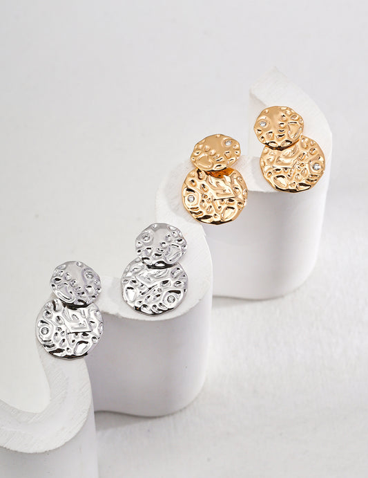 Sculptured statement earrings in gold and silver with a circular design.