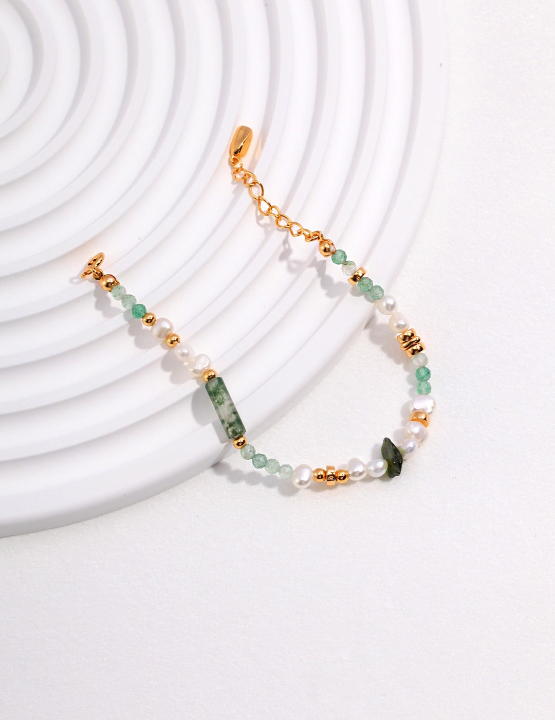 Green and gold bracelet with pearl and stone, elegant jewelry piece for special occasions.