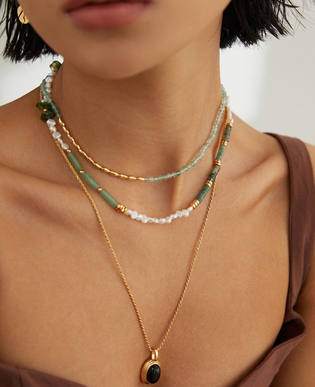 Green necklace and gold chain on woman, complemented by gold Green Strawberry Quartz necklaces.