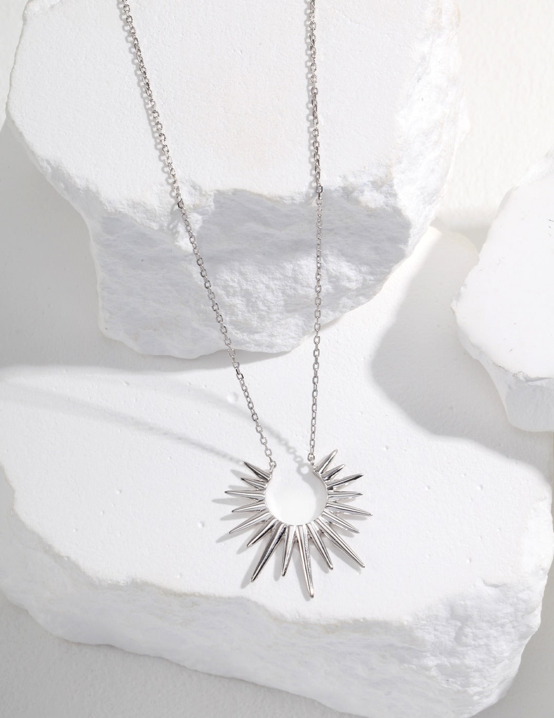 Elevate your look with a silver necklace adorned with a radiant sunraydesign, a symbol of warmth and positivity.