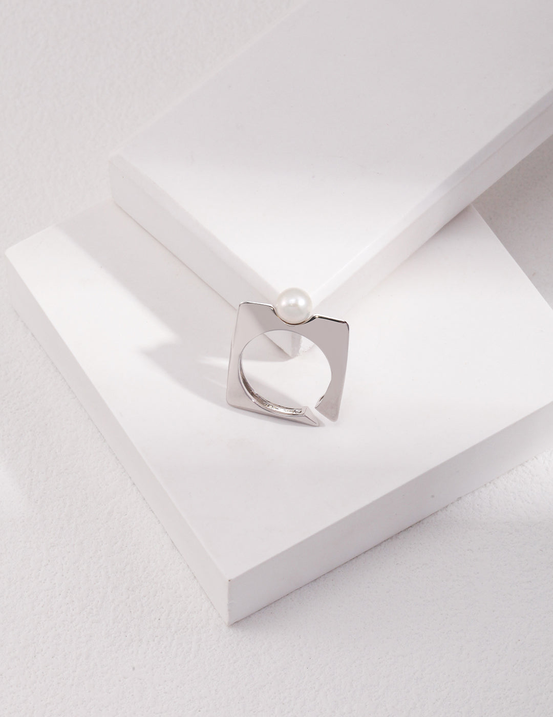 Square silver ring featuring freshwater pearl on white box.