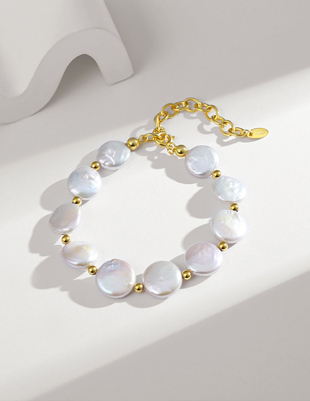 A stunning white pearl bracelet with a gold plated chain, adorned with round baroque pearls.