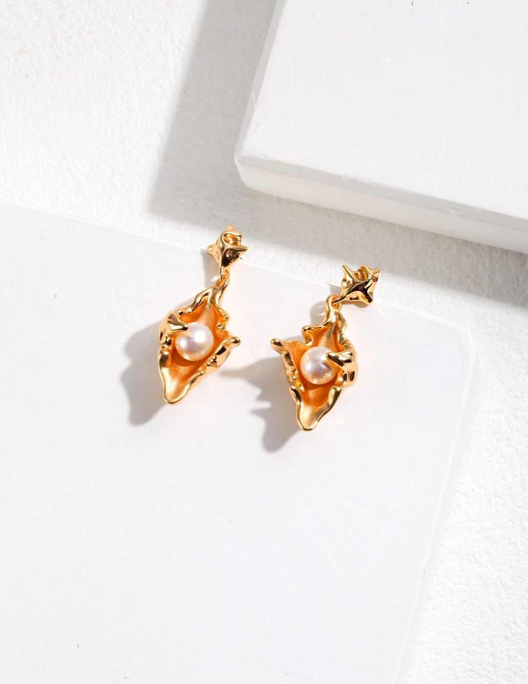 Luxurious gold plated conch earrings adorned with freshwater pearls.