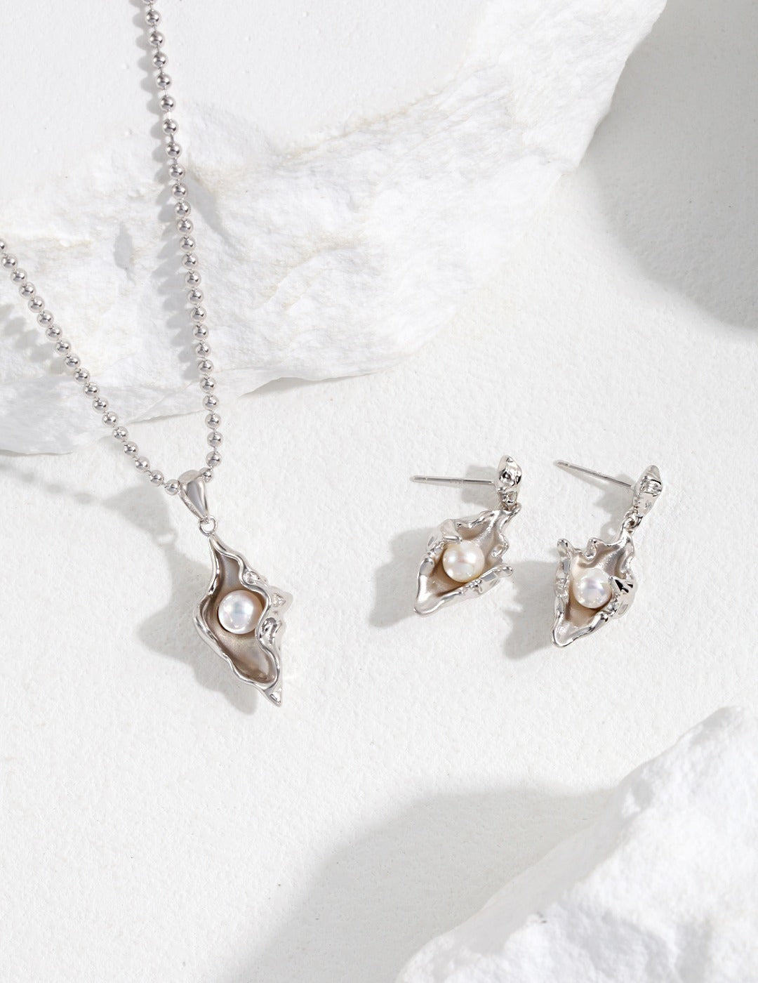 Silver elegant earrings and a matching necklace featuring lustrous pearls, showcasing timeless beauty and sophistication.