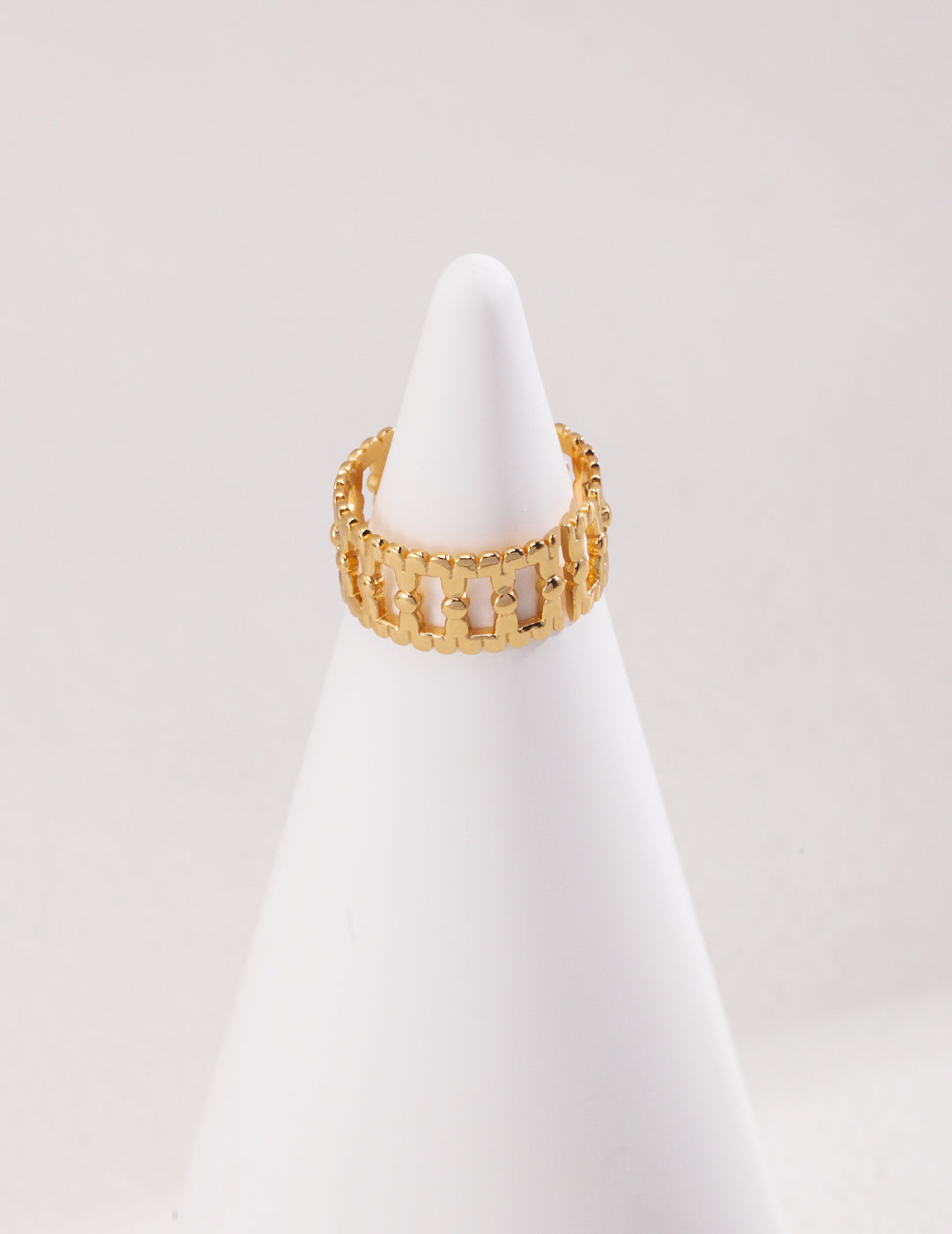 A gold hollow ring placed on a white cone, creating an elegant and striking contrast.