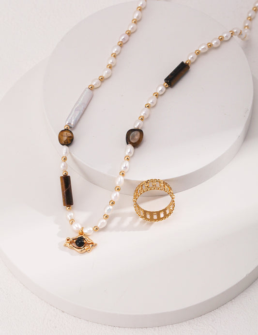 Elegant gold ring and necklace featuring pearls and tiger's eye stone..