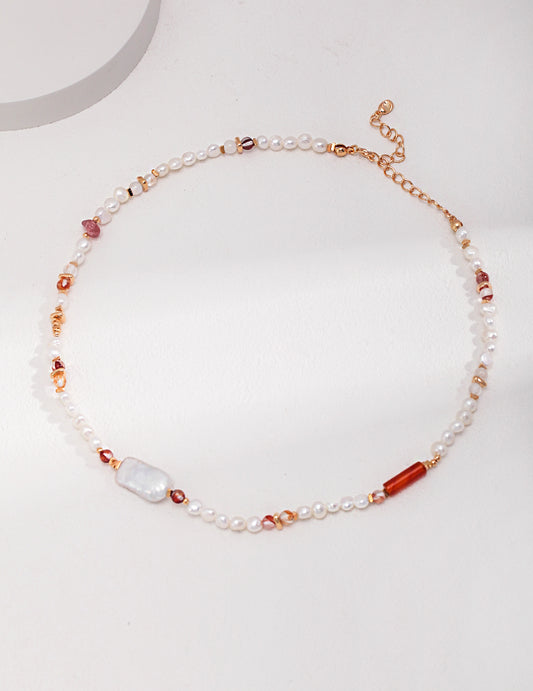 A vibrant freshwater pearl necklace with strawberry quartz and colorful beads on a white surface.