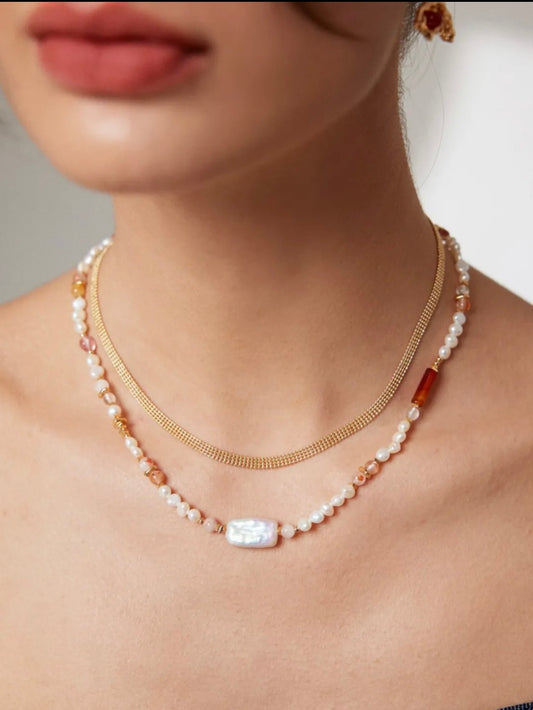 Layered necklace featuring pearls, a gold chain, and strawberry quartz accents for a stylish and elegant look.
