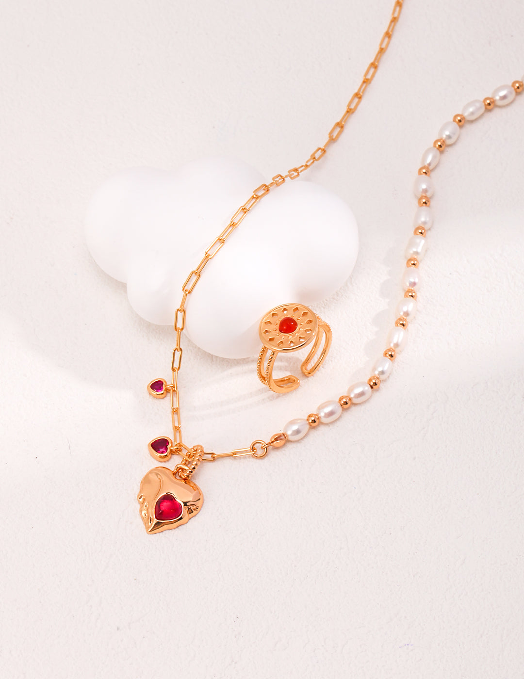 Elegant gold necklace adorned with a vibrant red heart and a whimsical cloud, perfect for adding a touch of romance.