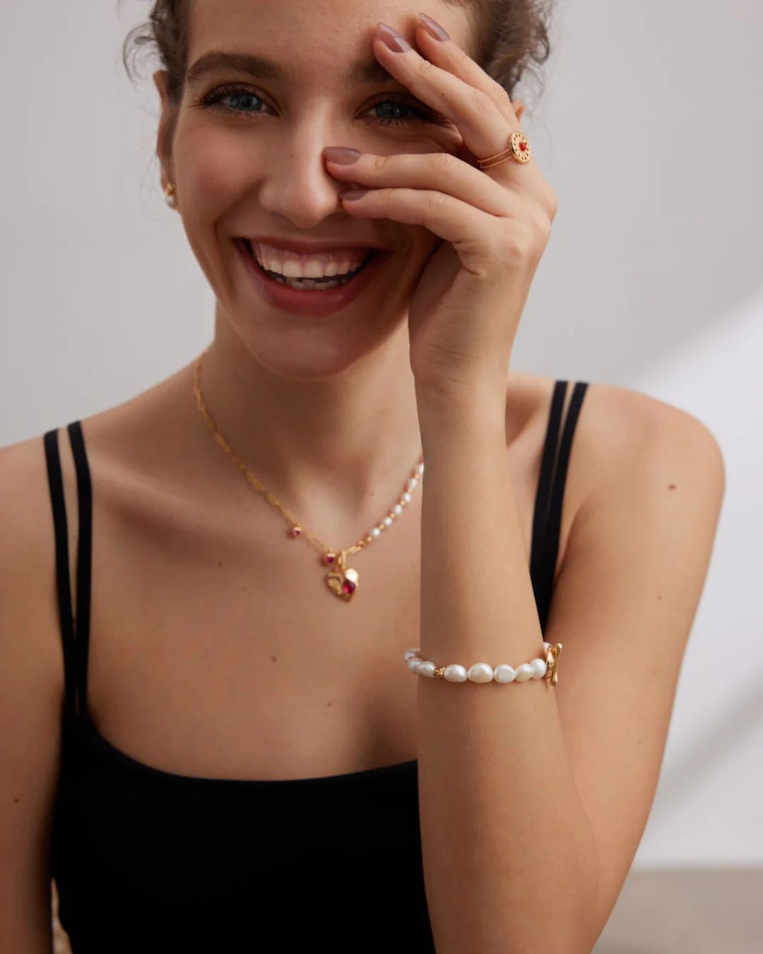 A joyful woman wearing a pearl necklace, radiating happiness and sophistication in her expression.