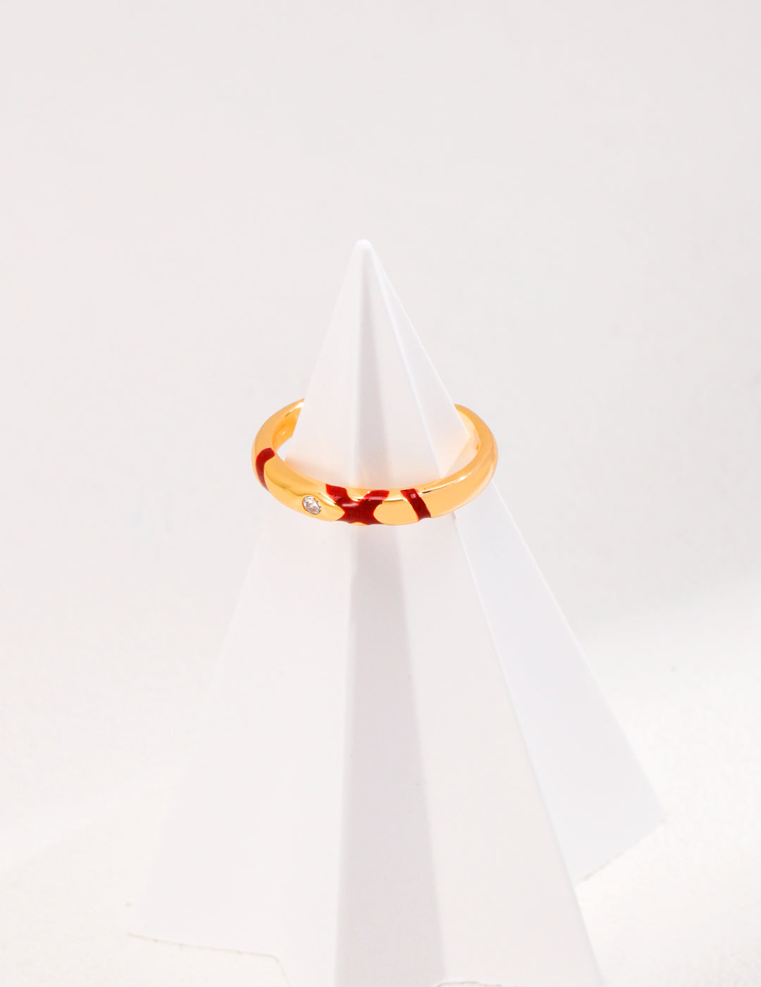 A gold plated ring adorned with splashes of red and cubic zirconia.