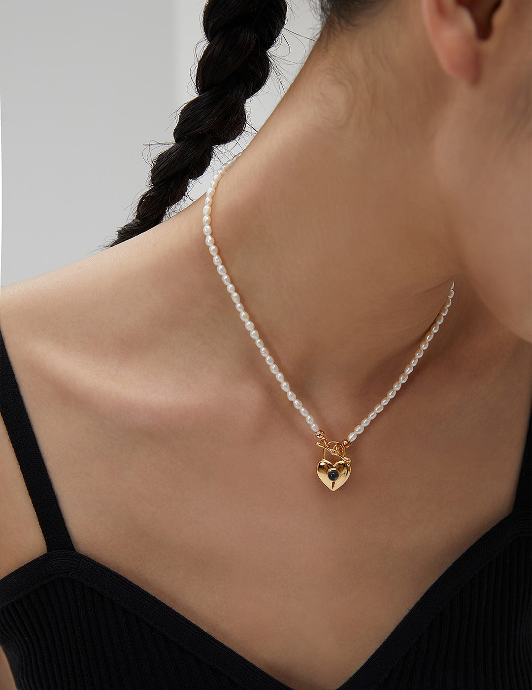 Woman in gold plated heart necklace with rice pearls.