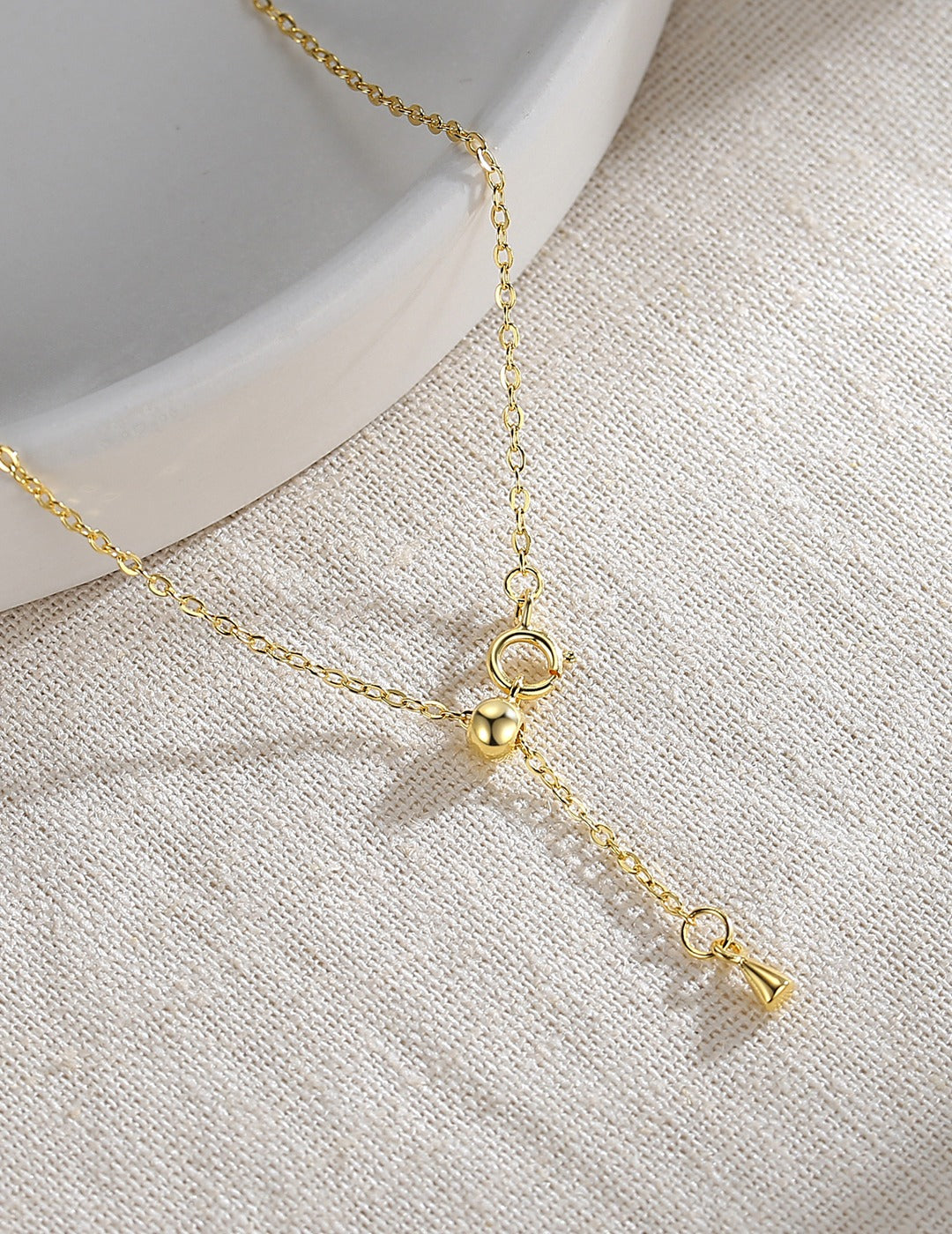 A simple gold plated necklace with a clasp hanging from a delicate chain.