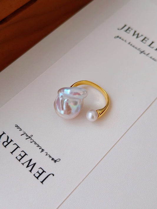 A stunning baroque pearl ring placed on an open book, highlighting its distinctive beauty and the texture of the pages.