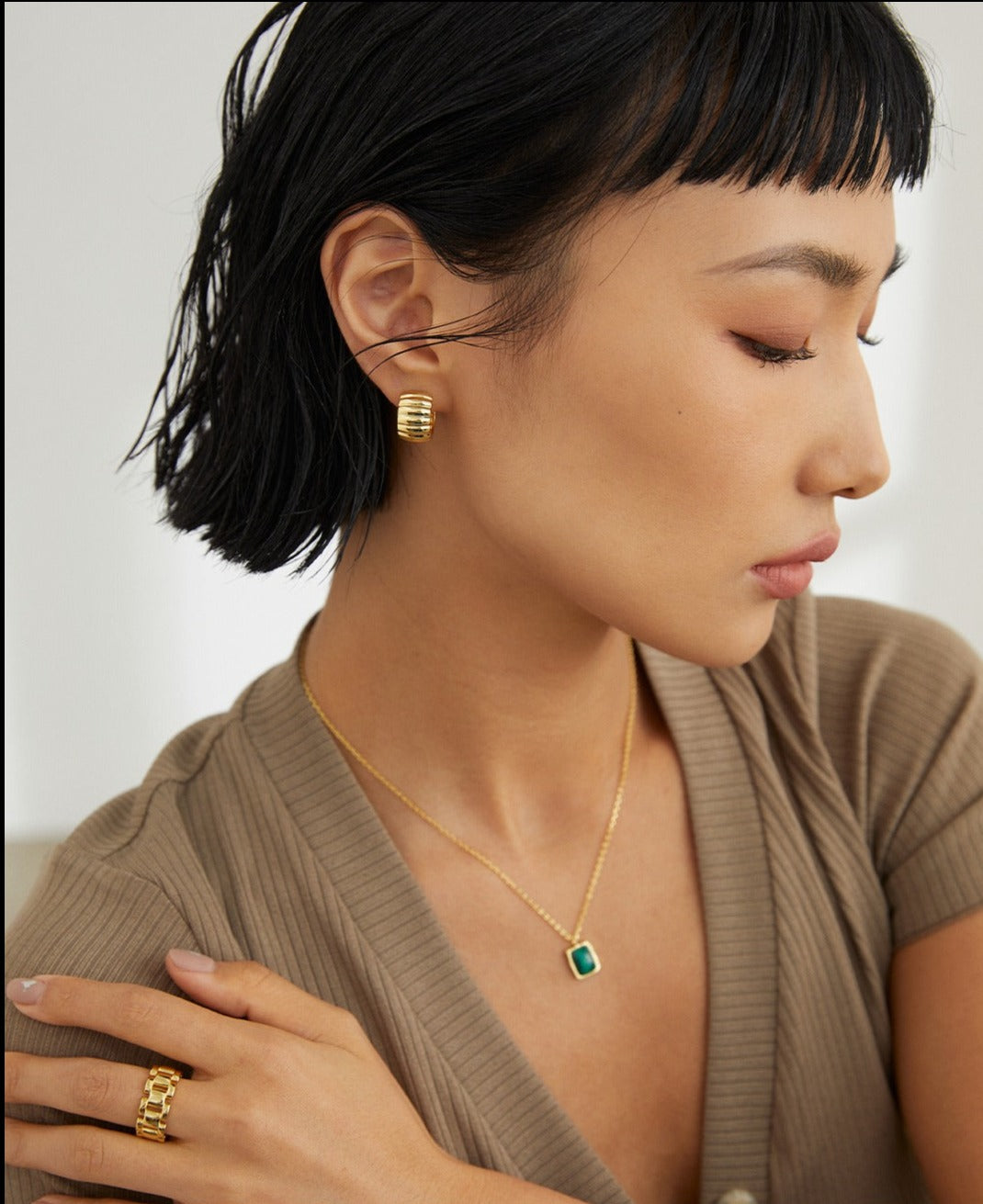 Lady with gold jewelry, featuring a gold ring.