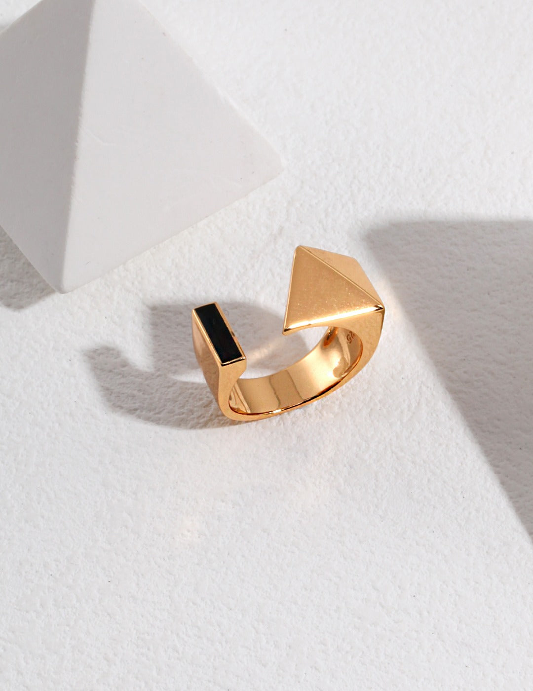 A gold enamel ring with a triangle shape design.