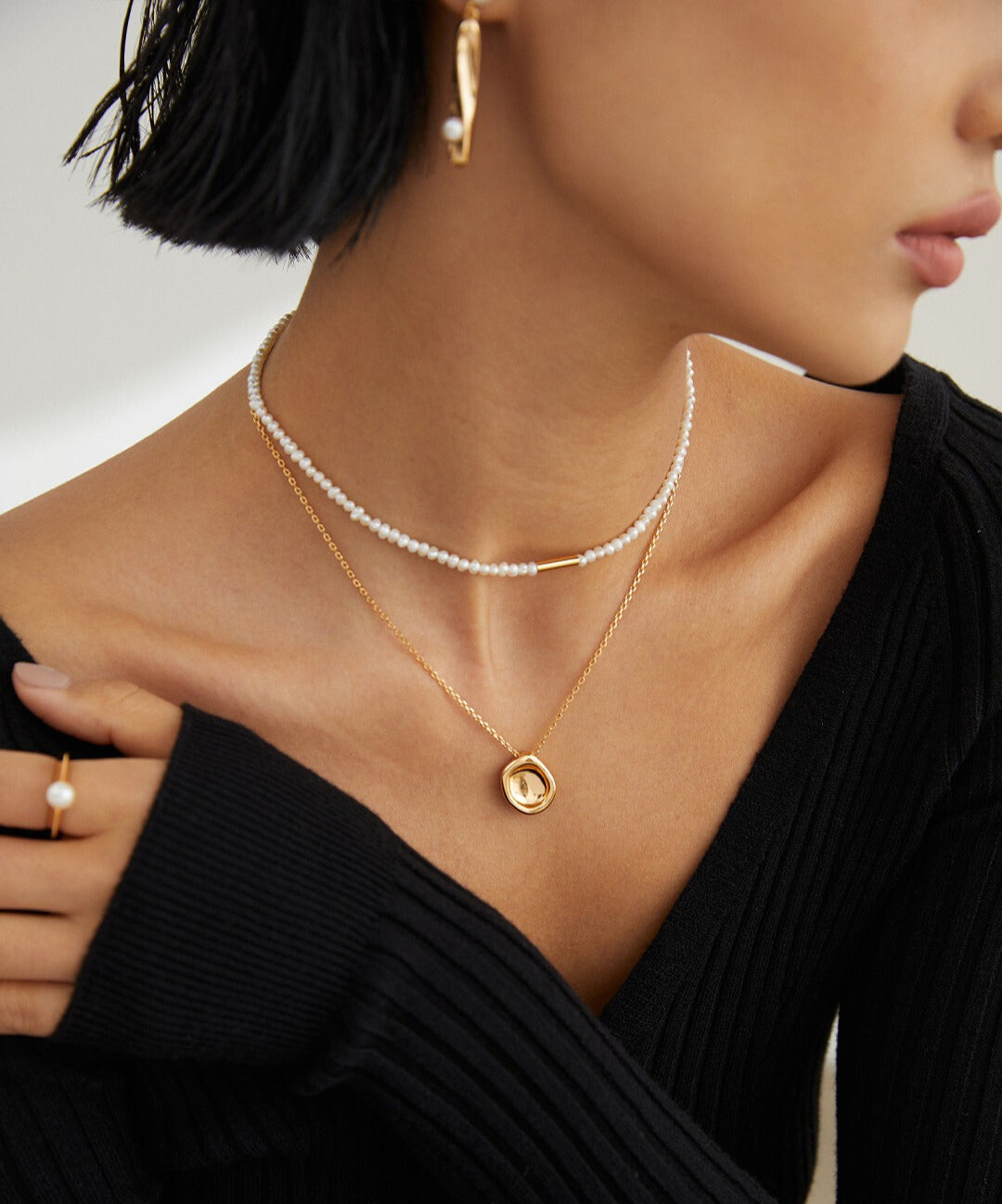 Fashionable woman wearing gold necklaces and black sweater.