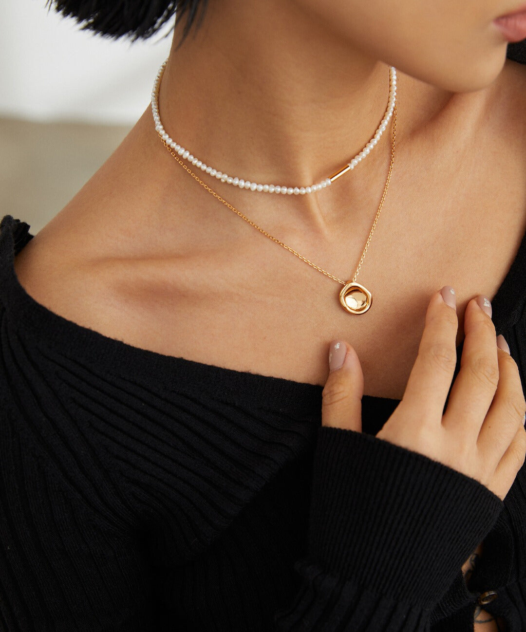 Woman adorned in layers of gold and pearl necklaces.