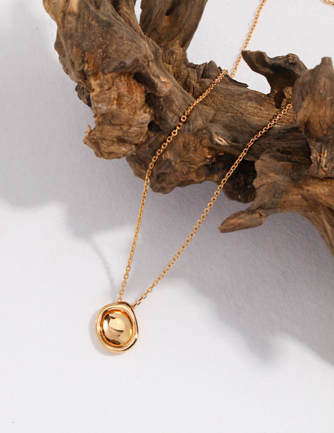 Shiny gold pendant featuring circle design on necklace.