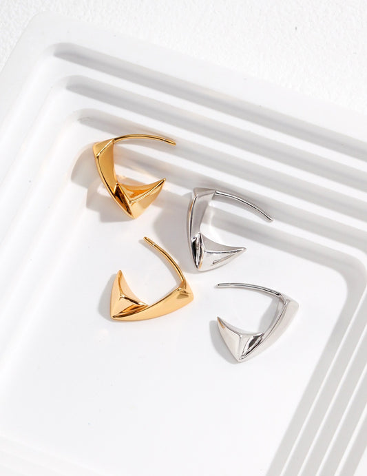 Gold and silver triangular hoop earrings arranged neatly on a white plate.