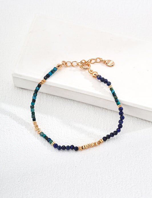 A blue and gold bracelet elegantly rests on a clean white surface, showcasing its vibrant colors and design.