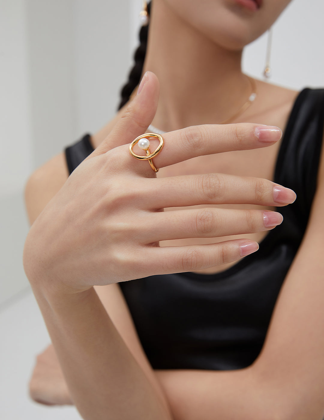 A stylish woman flaunting a black top and a gold ring with a stunning freshwater pearl.