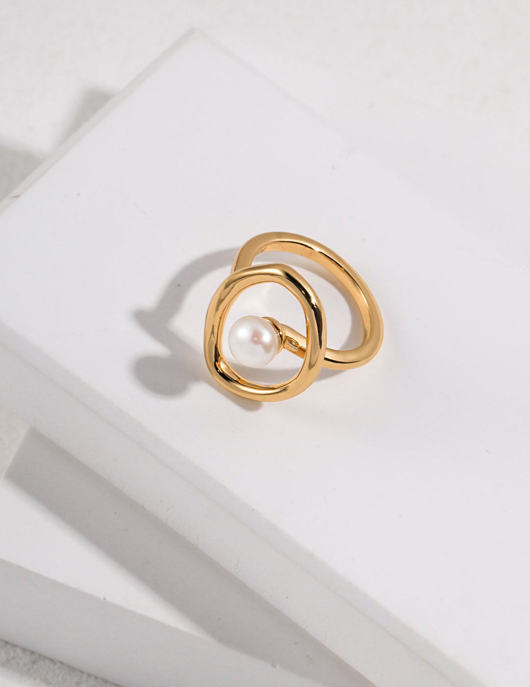 Circular gold ring featuring a lustrous freshwater pearl.