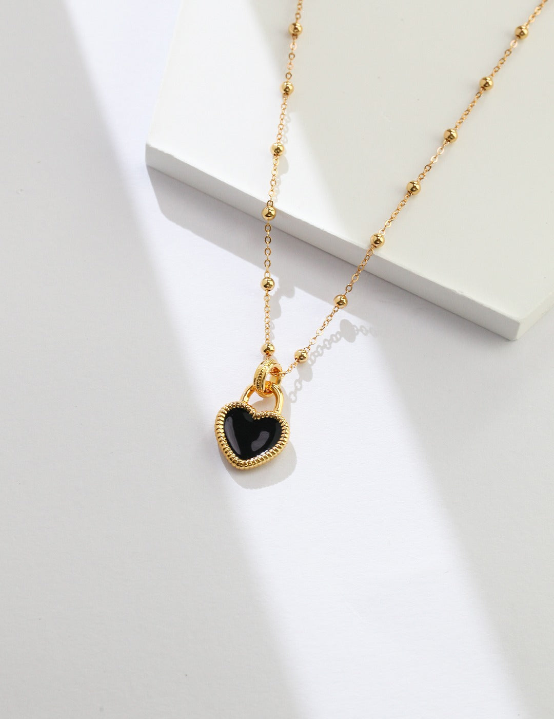 Elegant gold chain with black heart pendant.