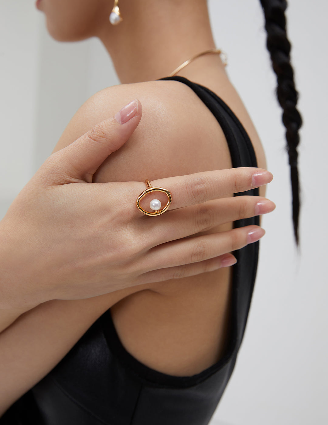 A model showcasing a gold ring with a freshwater pearl at its center, adding elegance to her hand.