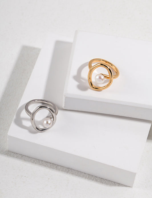 Two elegant rings: one silver, one gold. Each features a freshwater pearl set in a hollow circular design.