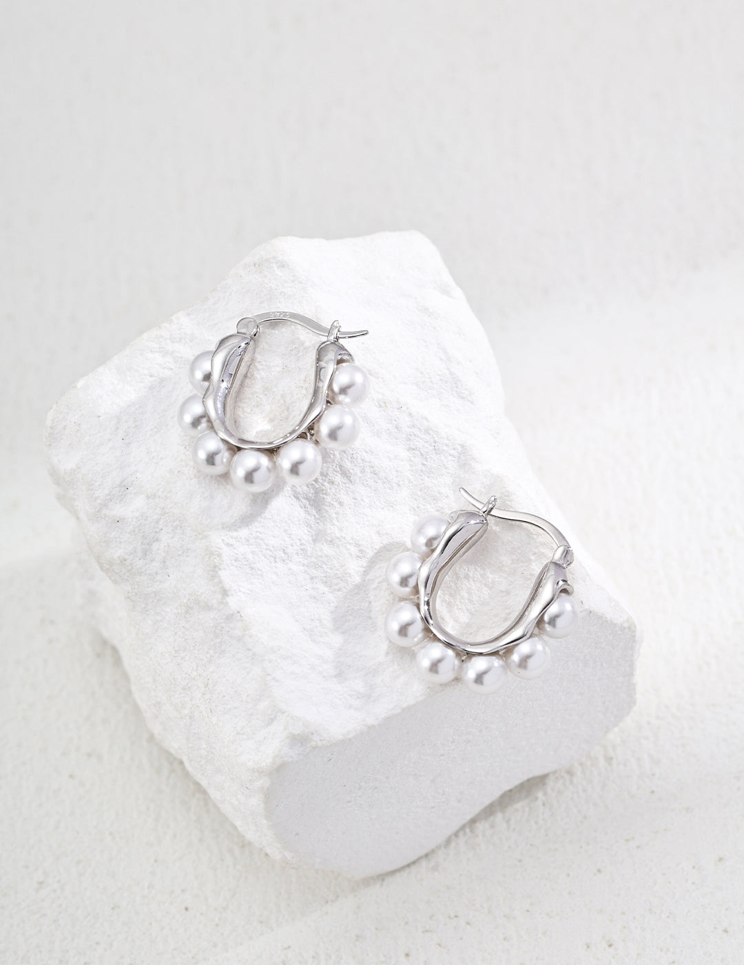 Silver hoop earrings featuring beautiful shell pearls, perfect for adding a touch of elegance to any outfit.