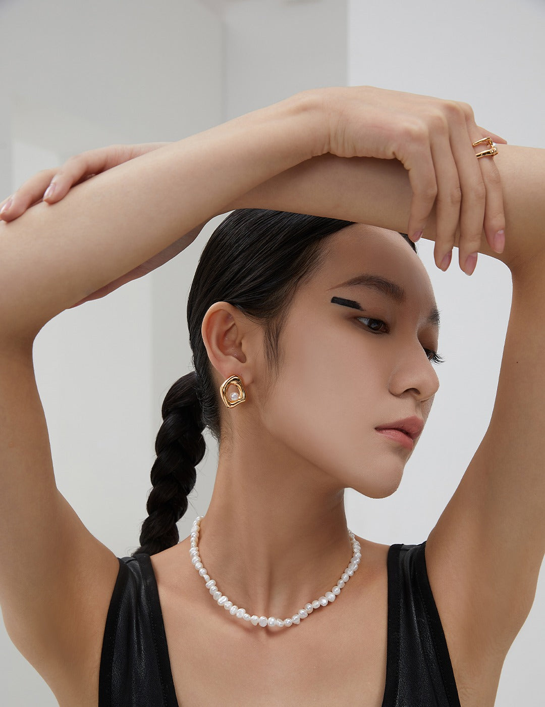 Side profile of a model wearing the Miley Necklace and gold statement earrings, emphasizing the delicate, classic length of the pearl strand.