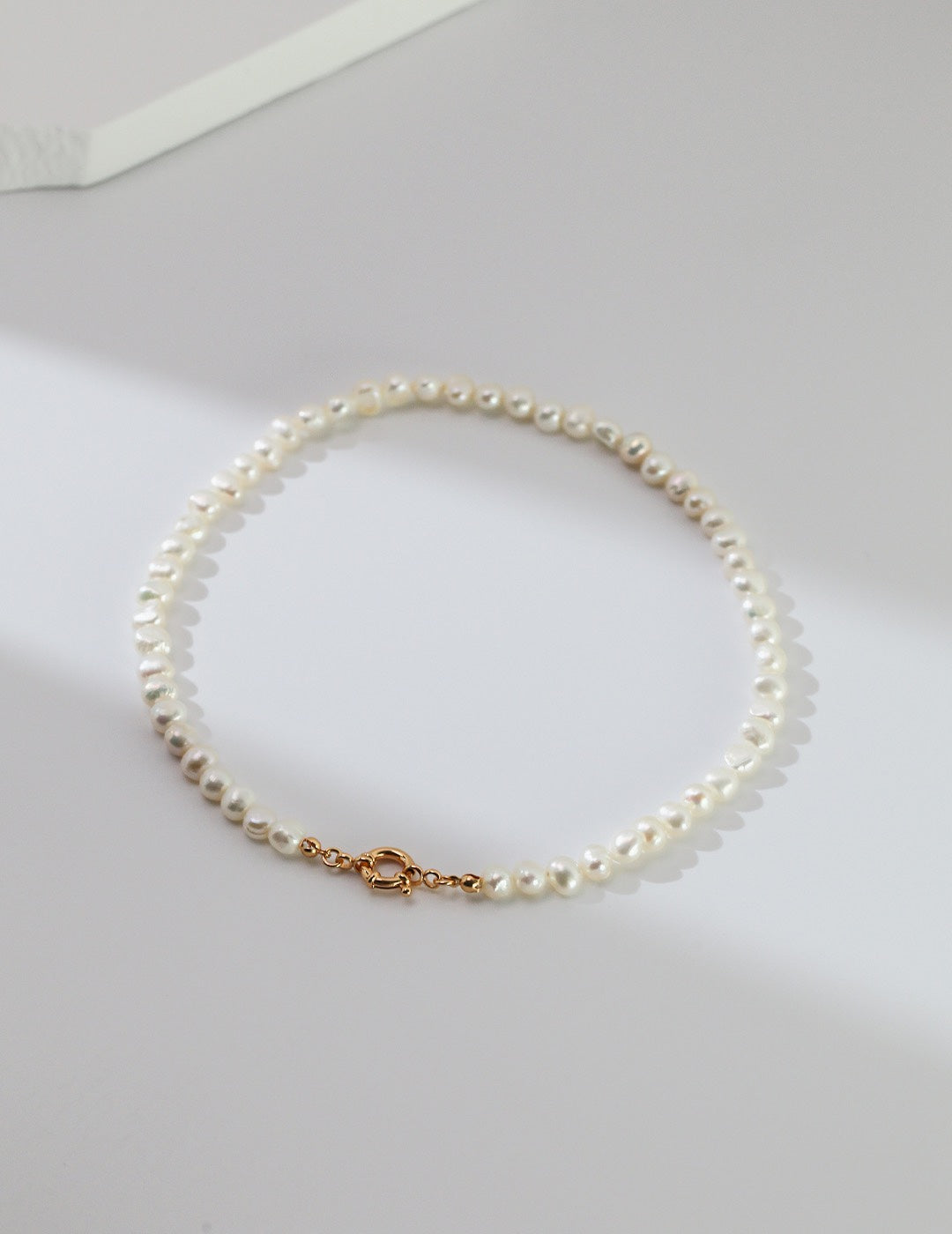 Minimalist view of the Miley Necklace on a clean white surface, highlighting the uniform luster of the pearl strand.