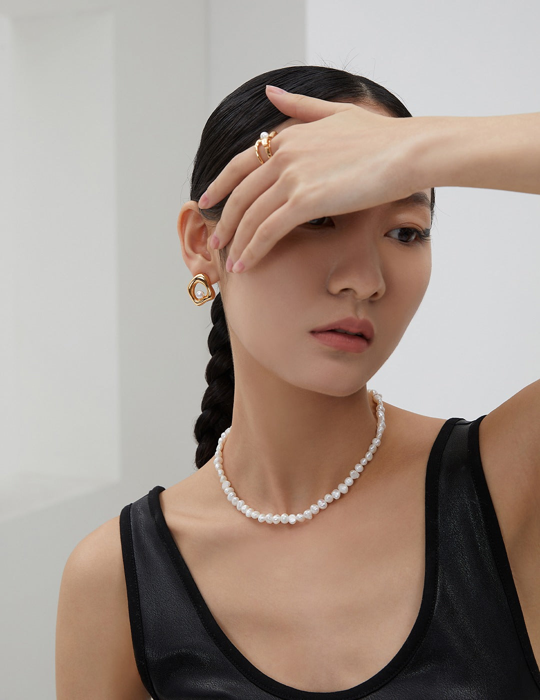 A model wearing the Miley Necklace, styled with gold geometric earrings and a black top, showcasing the elegant fit around the neck.