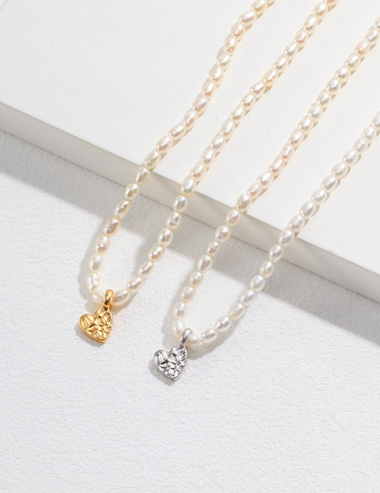 Two elegant pearl necklaces with heart charms, one in gold and the other in white, exuding grace and sophistication.