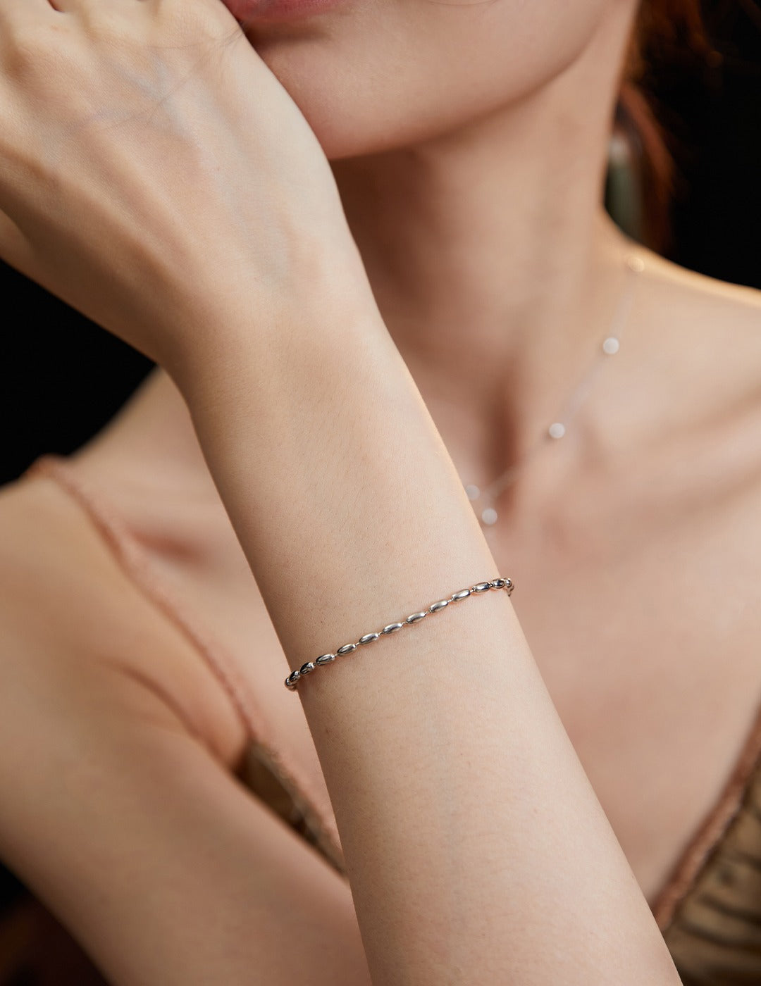 Silver bracelet on woman's wrist, highlighting silver plated dainty beads.