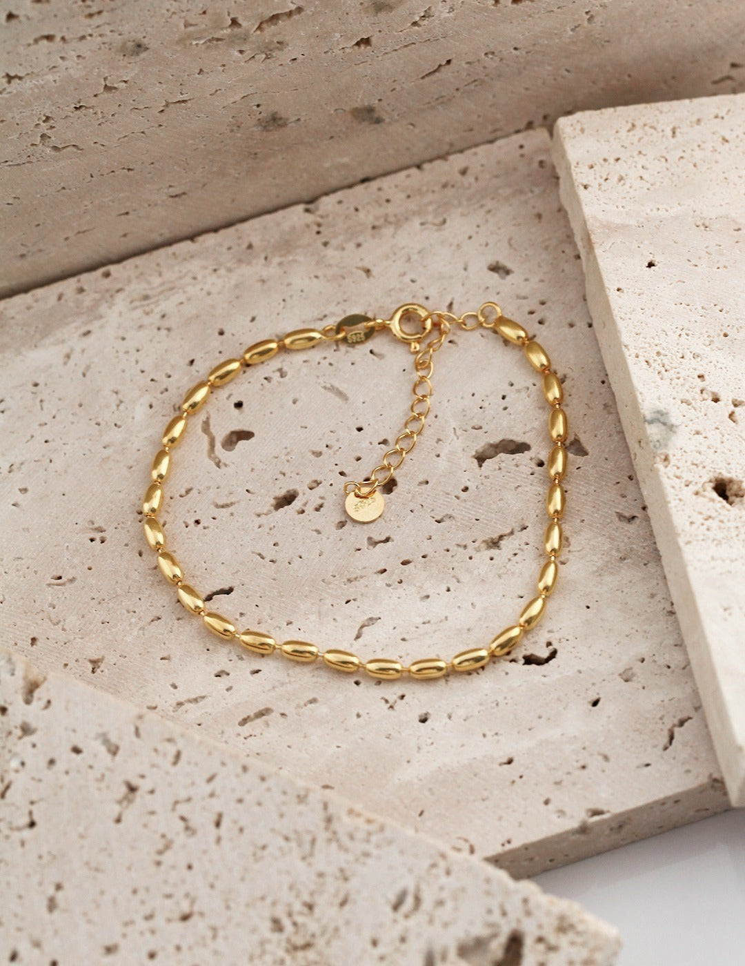 Elegant gold chain bracelet with dainty beads on stone.