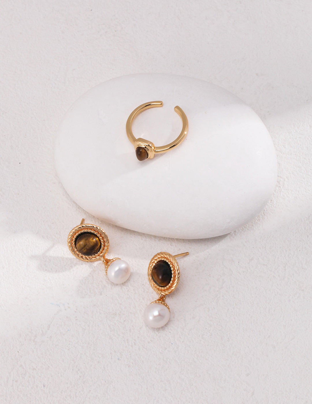 Stunning gold earrings with tiger's eye and freshwater pearls, accompanied by a beautiful ring.