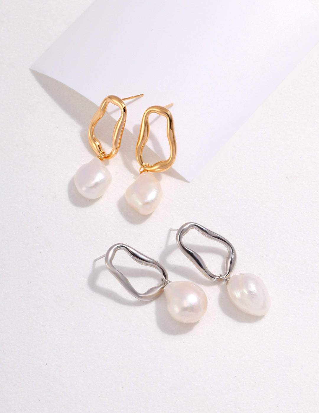 Stylish silver and gold earrings adorned with white baroque pearls.