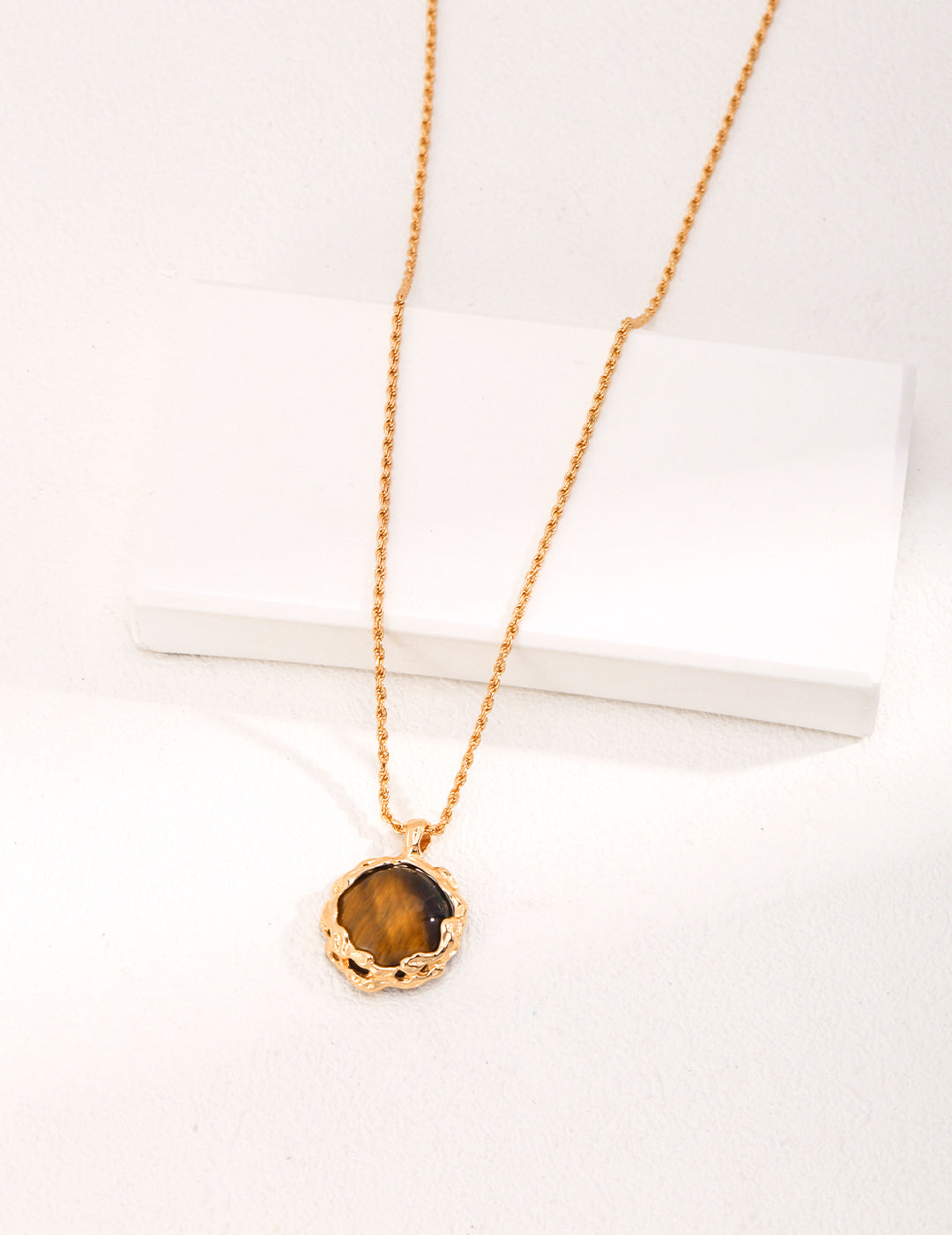 A stunning gold pendant with a captivating tiger's eye stone, adorning a gold plated necklace.