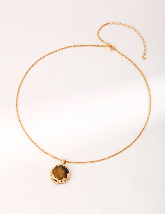 Gold necklace with tiger's eye pendant and small disc charm.