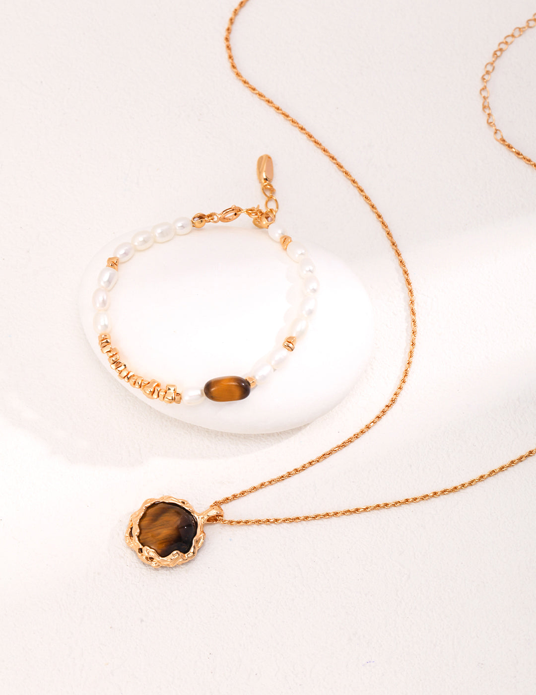 A beautiful gold plated necklace featuring a mesmerizing tiger's eye pendant, accompanied by a matching bracelet.